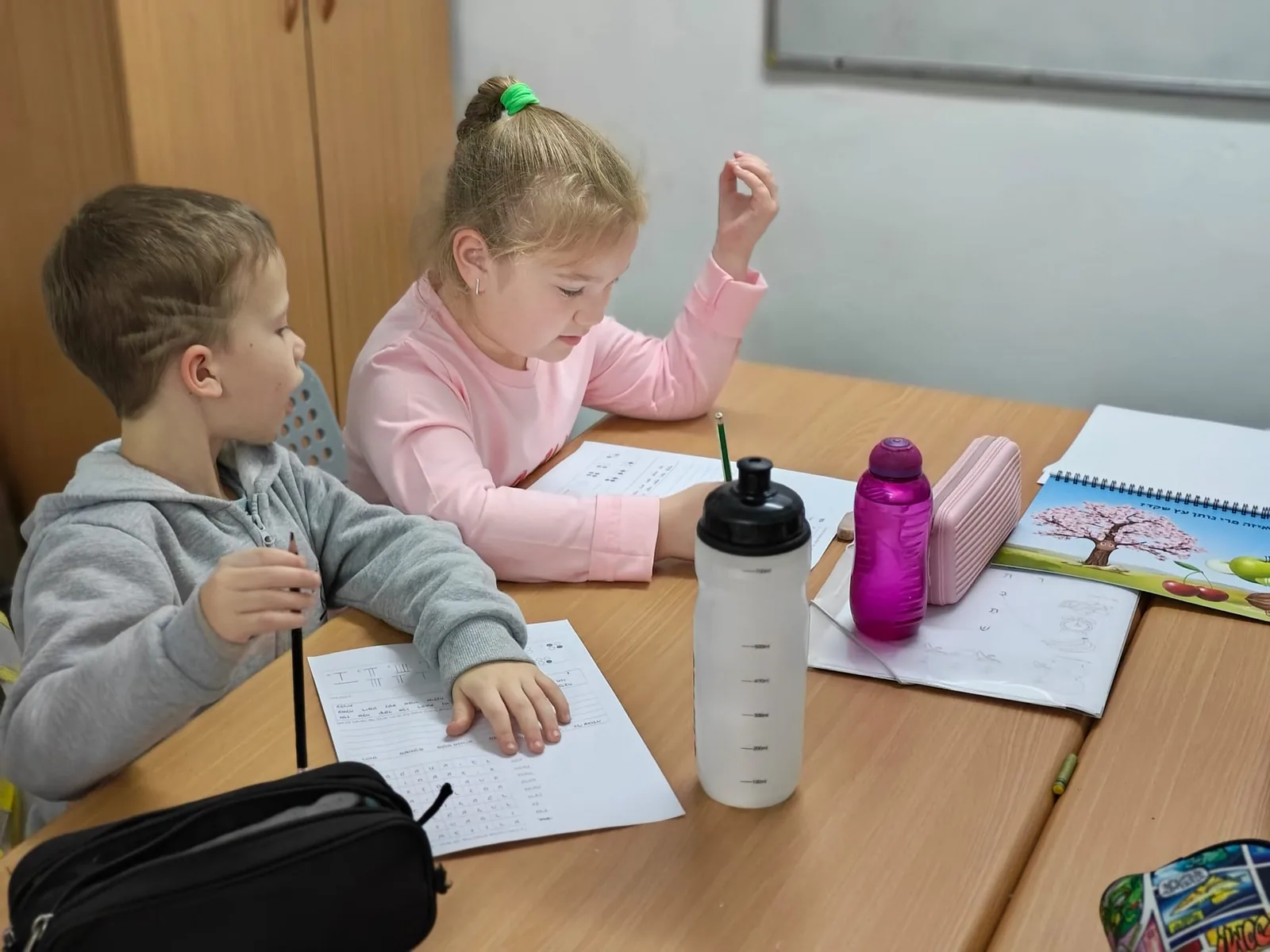תלמידי כיתה א׳ פותרים משימות ליד השולחן